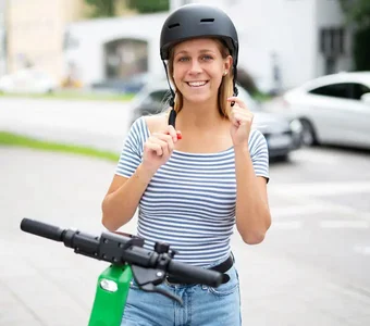 Frau zieht Helm an um E-Scooter zu fahren