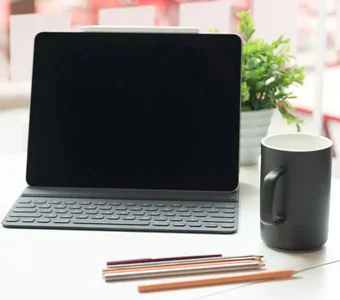 Tablet PC steht auf Tisch in Café mit Tasse und Stiften