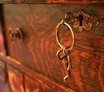 Antike abschließbare Kommode aus roten Holz und goldenen Verzierungen - Nahaufnahme des Schlüssellochs, Schüssel. und Griff