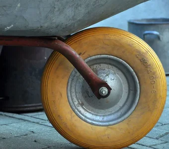 Eine Schubkarre mit einen gelben Reifen steht auf einem Steinboden