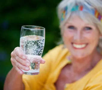 Fröhliche Frau mit einem Glas Wasser in der Hand