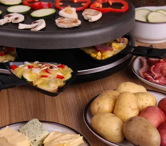 Ein Raclette wird benutzt, um Speisen auf der Grillplatte und den Einschubfächern zuzubereiten
