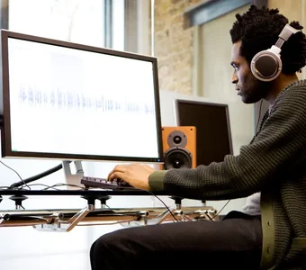 Junger Mann hört im Musikstudio mit seinen Over-Ear-Headphones