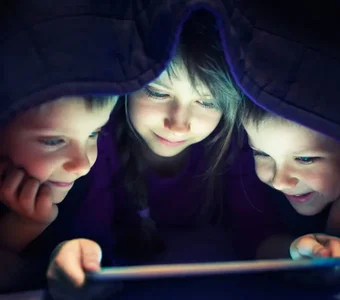Kinder spielen heimlich auf dem Tablet unter der Decke