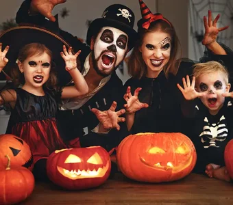 Fröhliche Familie mit Mutter, Vater und Kindern in Verkleidung und Schminke an Halloween