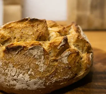 Auf einem Holzbrett liegt ein Brotlaib mit einer Brotkruste