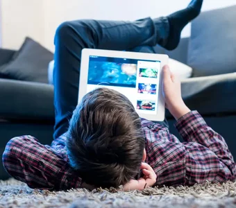 Ein junger Mann nutzt die gewonnene Freiheit und schaut sich Videos im Wohnzimmer an