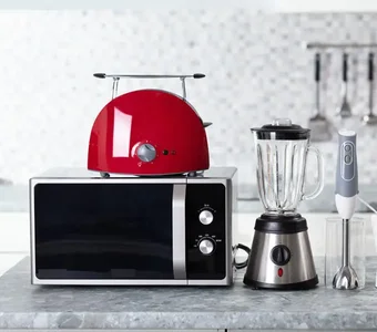 Mikrowelle, Toaster, Mixer, Pürierstab und Knetmaschine auf einer Küchenplatte
