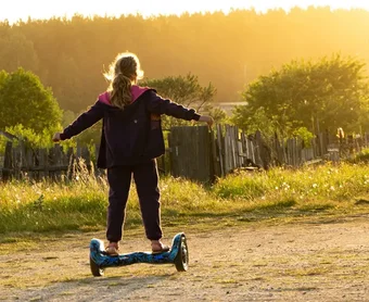 Mädchen fährt mit Hoverboard auf Gelände