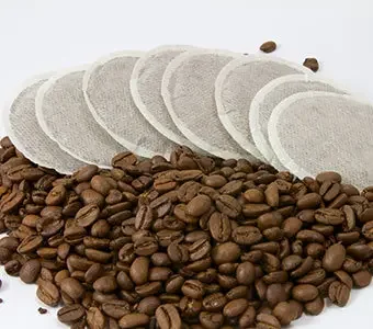 Nahaufnahme von Kaffeebohnen zusammen mit Kaffeepads.