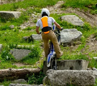 Ein Mann auf einem Mountainbike trägt einen Protektor am Rücken während er einen steinigen Hügel hinauffährt
