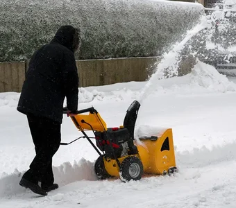 Ein Mann räumt mit einem Schneefräser seine Auffahrt frei