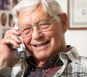 Ein älterer Mann freut sich über das Telefonat mit seinem Enkel