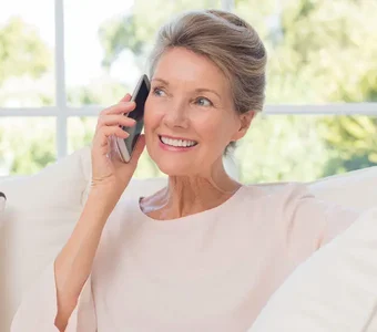 Eine ältere Dame genießt die einfache Kommunikation über ein großes Handy