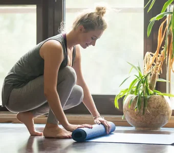 Frau roll ihre blaue Yogamatte ein