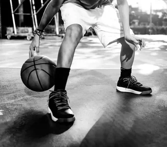Street-Basketballer dribbelt mit dem Ball. Nahaufnahme der Schuhe des Spieler in schwarz/weiß