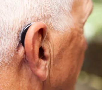 Älterer Herr mit einem Hörgerät am Ohr