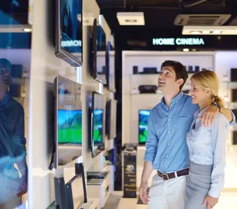 Zwei Personen stehen in einem Geschäft vor mehreren Fernsehern