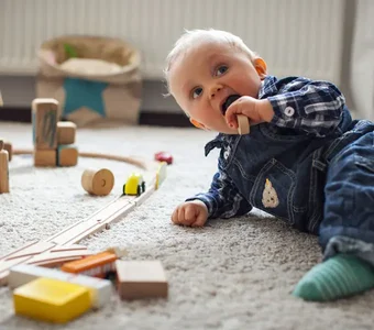 Ein Baby spielt mit einer Eisenbahn aus Holz