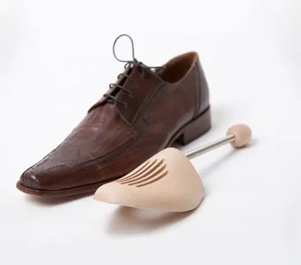 Brauner Schuh mit Schuhspanner aus Holz daneben