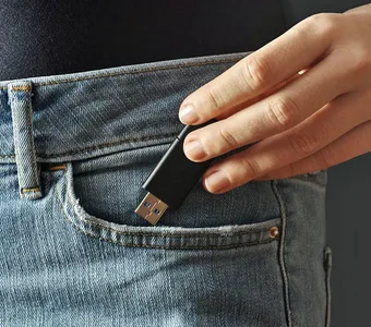 Ein USB Stick wird in eine Hosentasche gesteckt