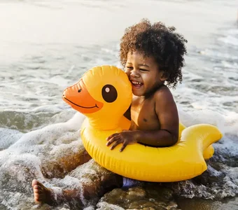 Ein Kleinkind sitzt in einem Schwimmreifen am Meer