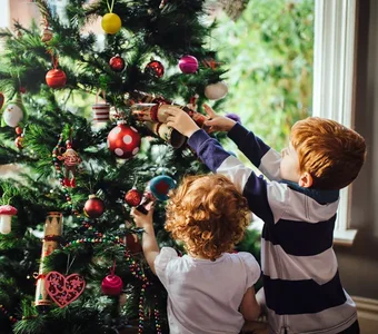 Großer Weihnachtsbaum wird von den kleinsten der Familie geschmückt