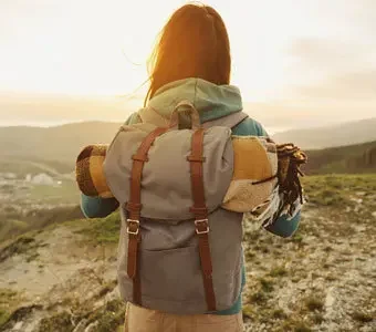 Rückansicht einer Frau mit Trekkingrucksack - im Hintergund weite Landschaften
