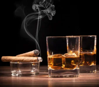 Zwei Gläser Scotch Whiskey und zwei Zigaretten vor einem schwarzen Hintergrund