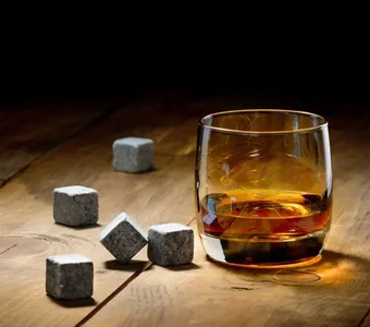 Whiskykühlsteine liegen neben einem Whiskyglas