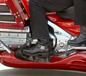 Aufnahme der Beine zweier Personen, welche auf einem Motorrad sitzen.