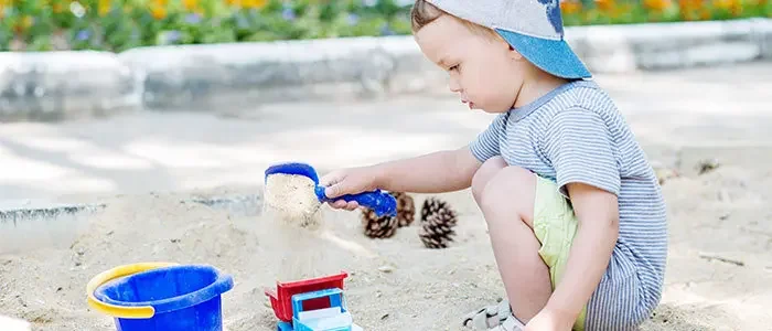 Aufnahme eines Kleinkindes, welches in einem Sandkasten spielt.