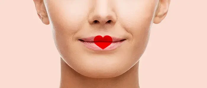 Nahaufnahme eines Mundes, auf welchem sich ein mit Lippenstift gemaltes Herz befindet.