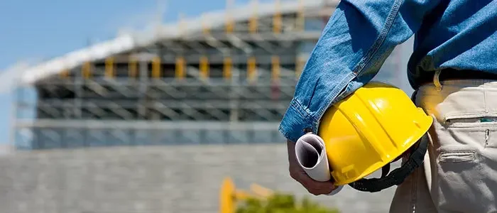 Person hält einen gelben Baustellenhelm im Arm