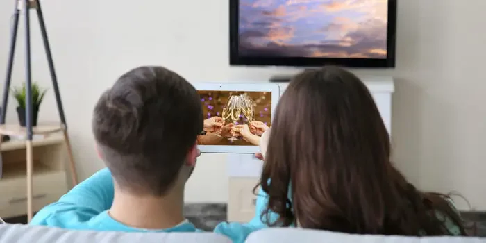 Mann und Frau auf Sofa betrachten Bild auf Tablet-PC.