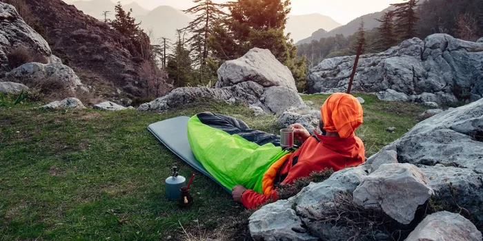 Wanderer in einem Schlafsack auf einer Isomatte auf einem Felsplateau