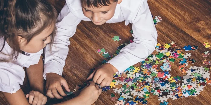 zwei Kinder puzzlen gemeinsam