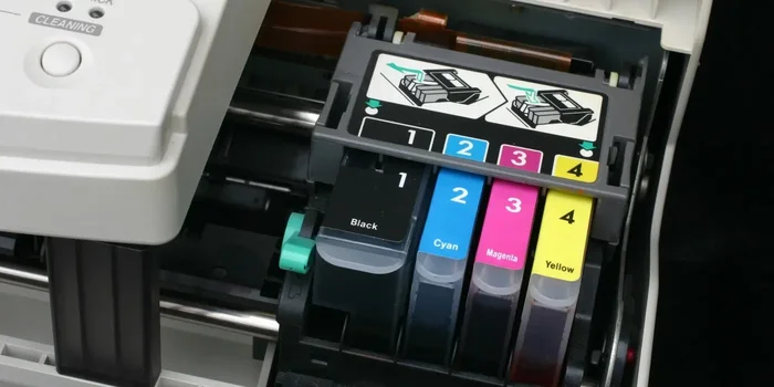 Nahaufnahme von einer schwarzen und drei bunten Druckerpatronen, die in einen Tintenstrahldrucker eingebaut sind