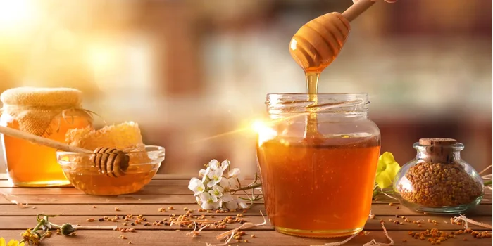 Hand, die mit einem Honiglöffel Honig aus einem Glas entnimmt