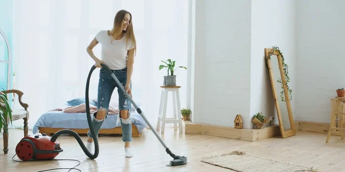 Frau saugt ihren Boden mit einem Bodenstaubsauger