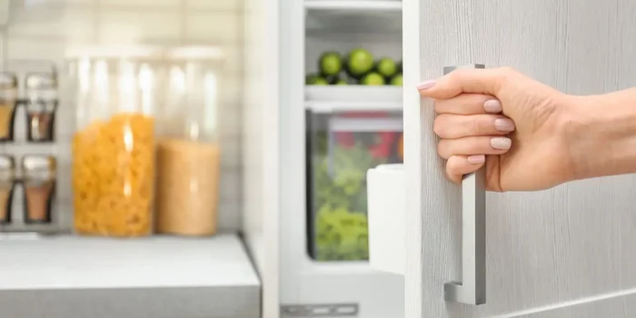 Eine Hand öffnet eine weiße Kühlschranktür