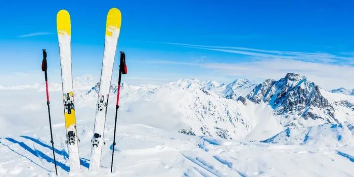 Weiß-gelbe Ski und Skistöcke stecken im Schnee