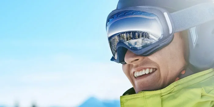 Nahaufnahme eines Mannes, der  in den Bergen eine Skibekleidung inklusive Skibrille trägt
