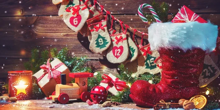 Adventskalender-Säckchen hängen an einer Schnur, Geschenke und ein Weihnachtsmannschuh stehen davor