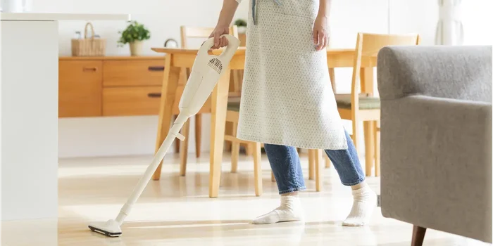 Frau reinigt die Wohnung mit einem elektrischen Besen oder Staubsauger