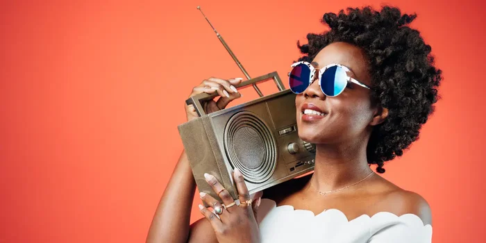 Frau mit Sonnenbrille trägt Radio auf Schulter