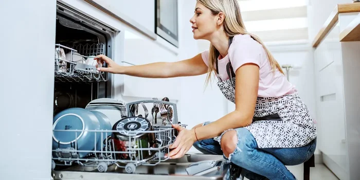 Frau räumt einen Geschirrspüler in der Küche ein