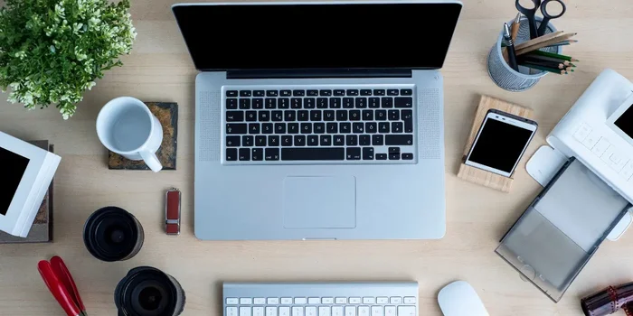 Schreibtisch mit Notebook, Tastatur, PC-Maus, Smartphone und weiteren Utensilien
