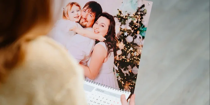 Eine Frau schaut sich einen Fotokalender mit einem fröhlichen Familienfoto an