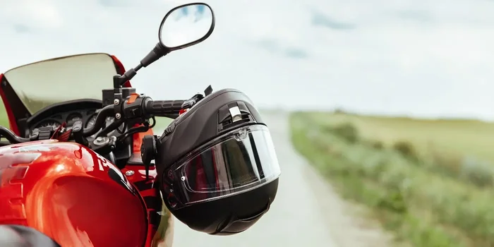 Aufnahme eines schwarzen Motorradhelms, der an dem Lenker eines roten Motorrads hängt